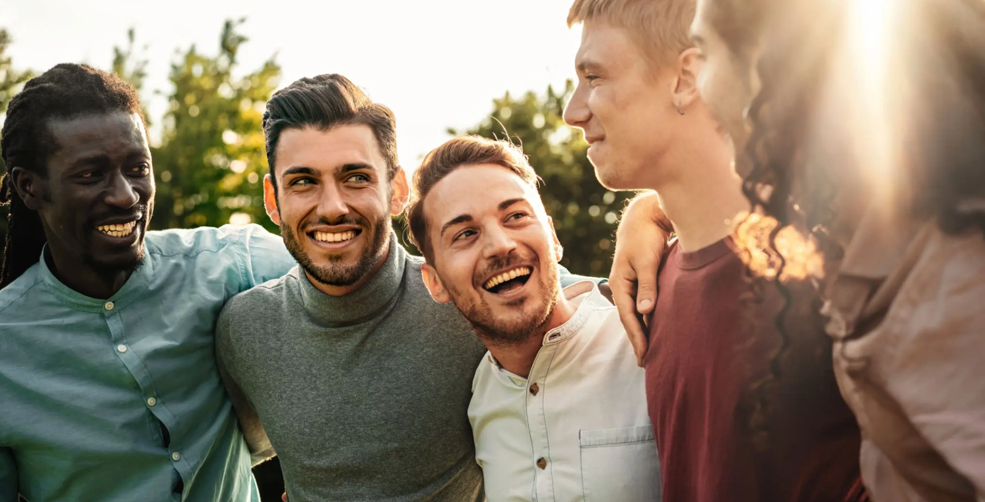 Group of friends laughing outdoors at sunset