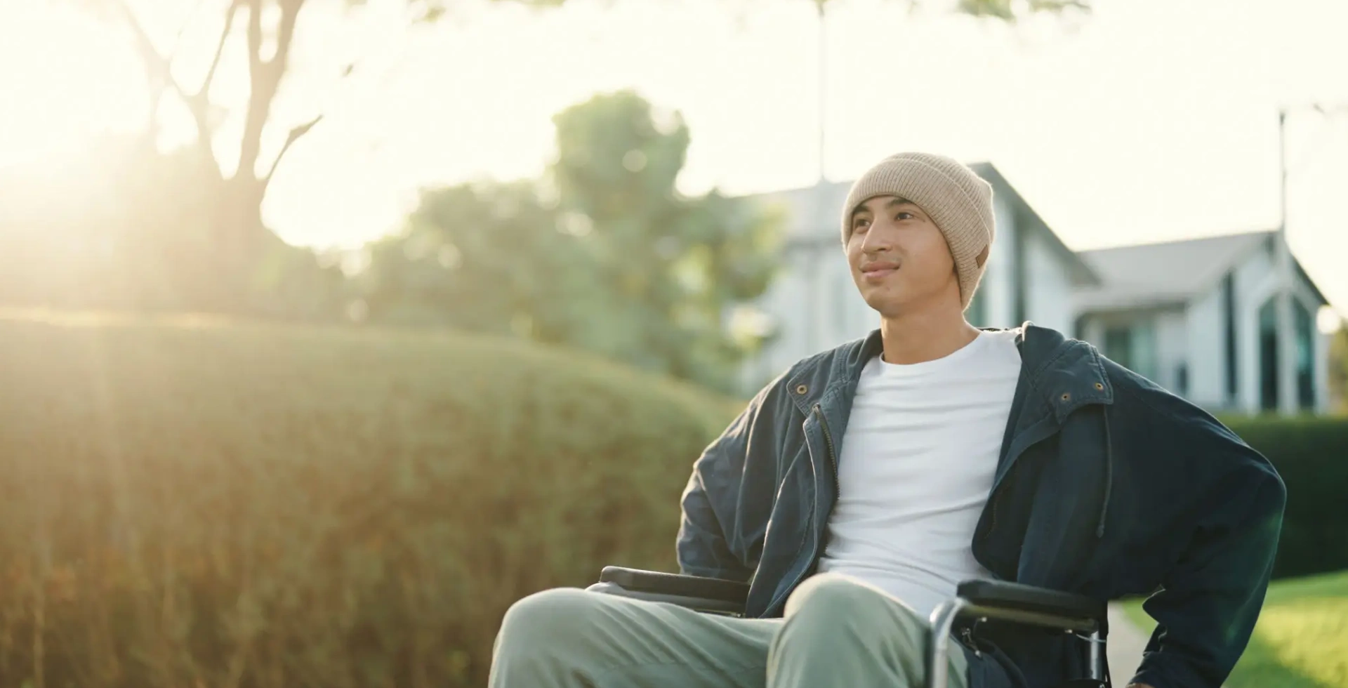 Young person smiling outdoors in sunlit yard