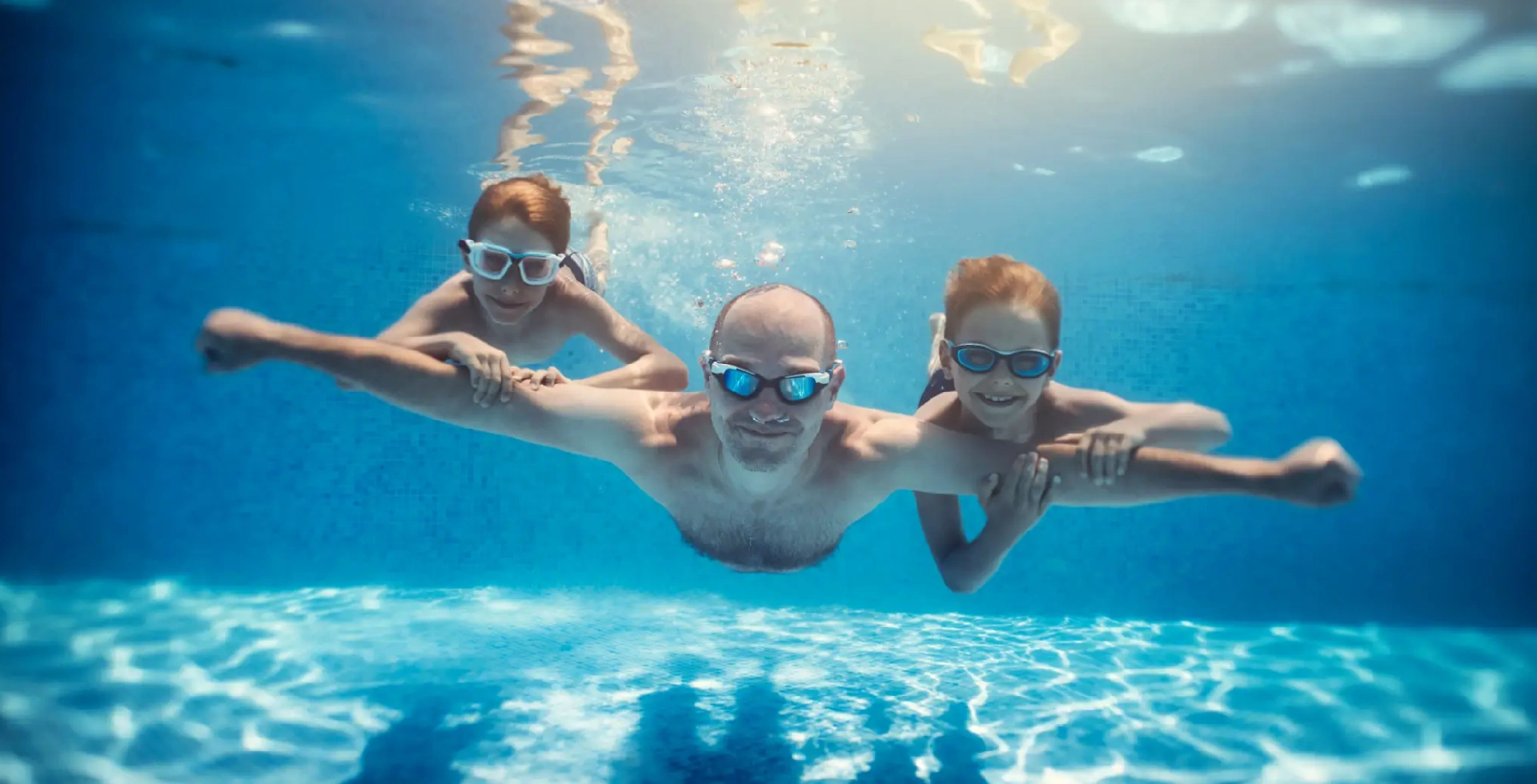 Man holding hands with two children underwater