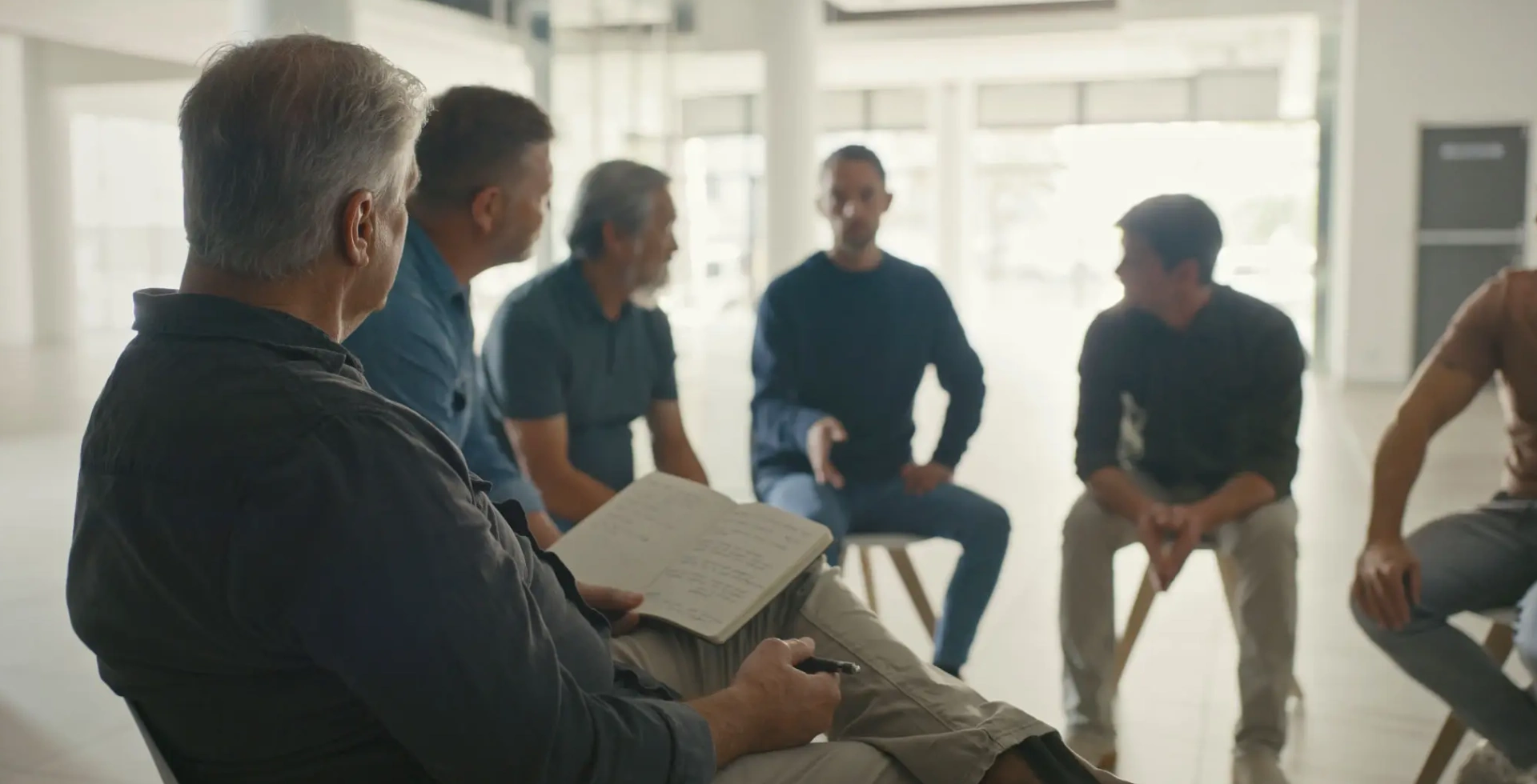 Men's group therapy session in bright room