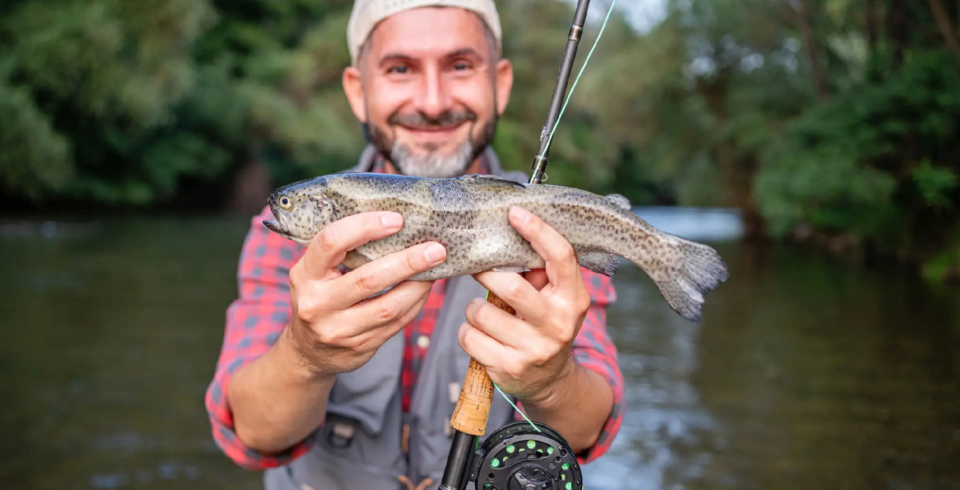 Fisherman holding trout by river