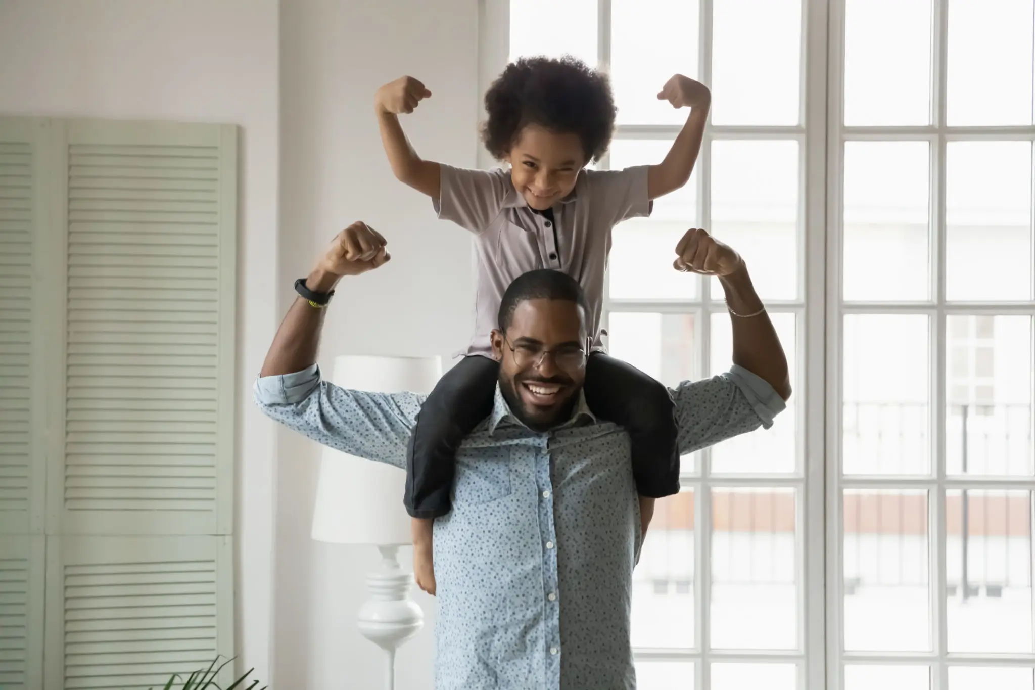Man carrying child on shoulders, both flexing
