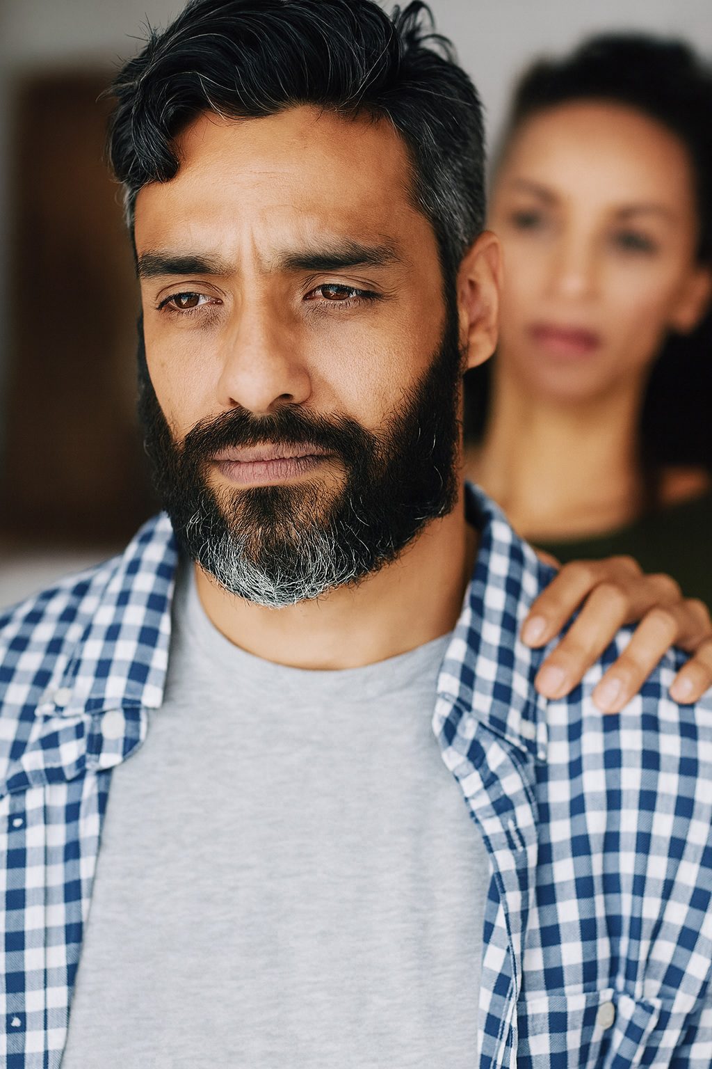 Bearded man looking pensive while partner comforts
