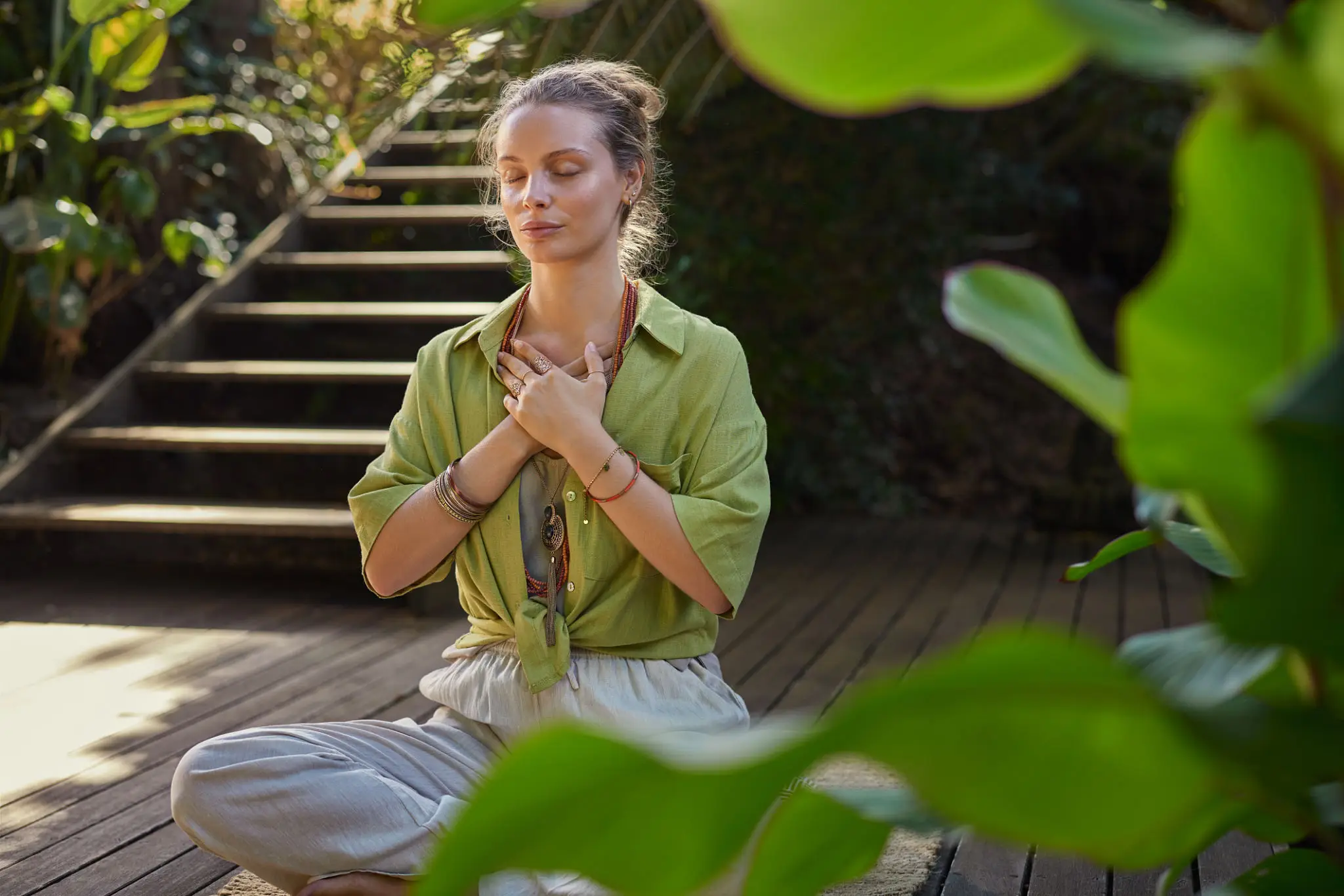 Woman meditating cross-legged on wooden deck
