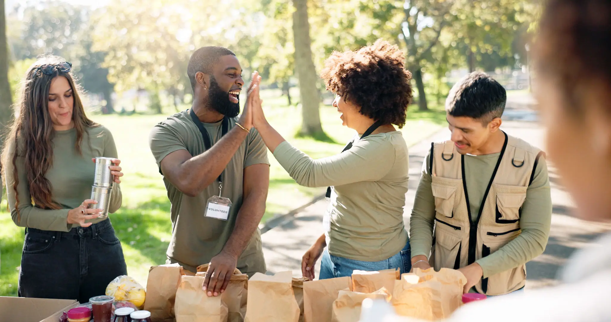 Volunteers packing food bags, high-fiving outdoors