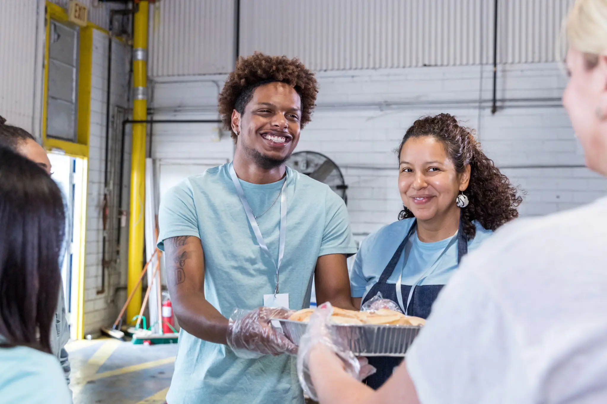 Volunteers handing meal tray at food distribution
