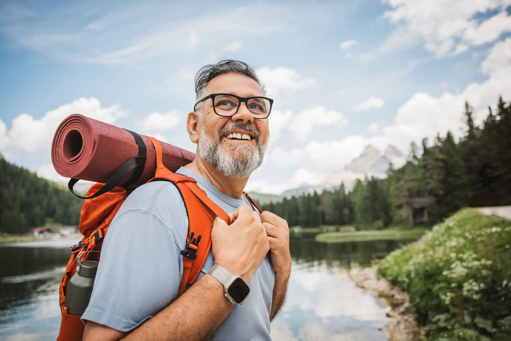 Smiling hiker with backpack by mountain lake