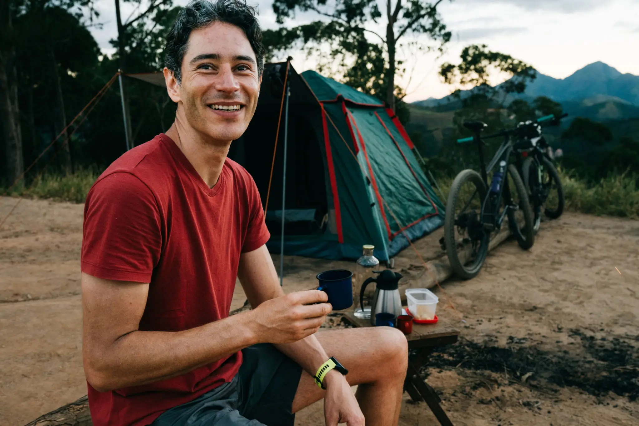 Smiling camper by tent and bicycles