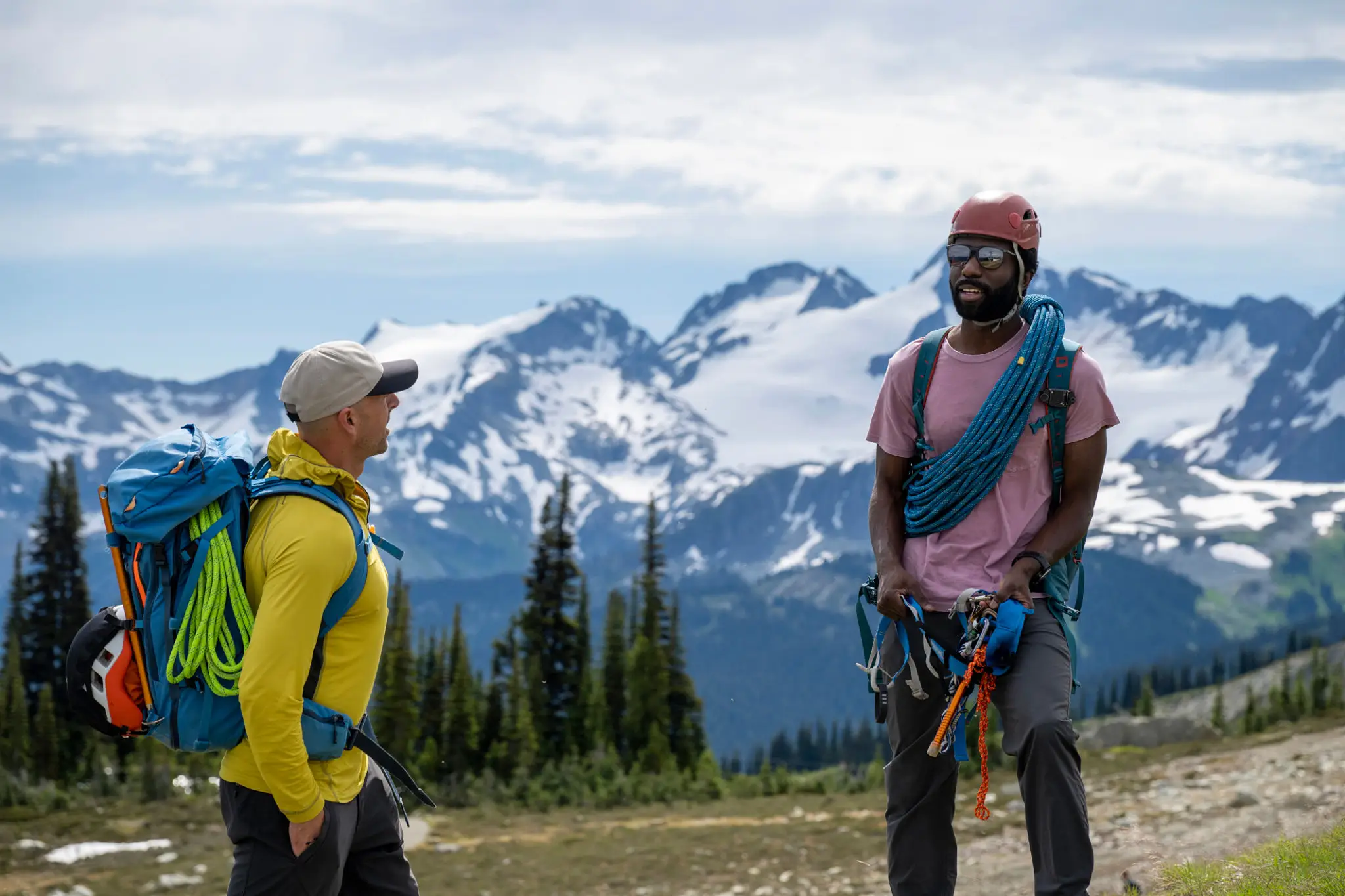 Two climbers with ropes near snow-capped mountains