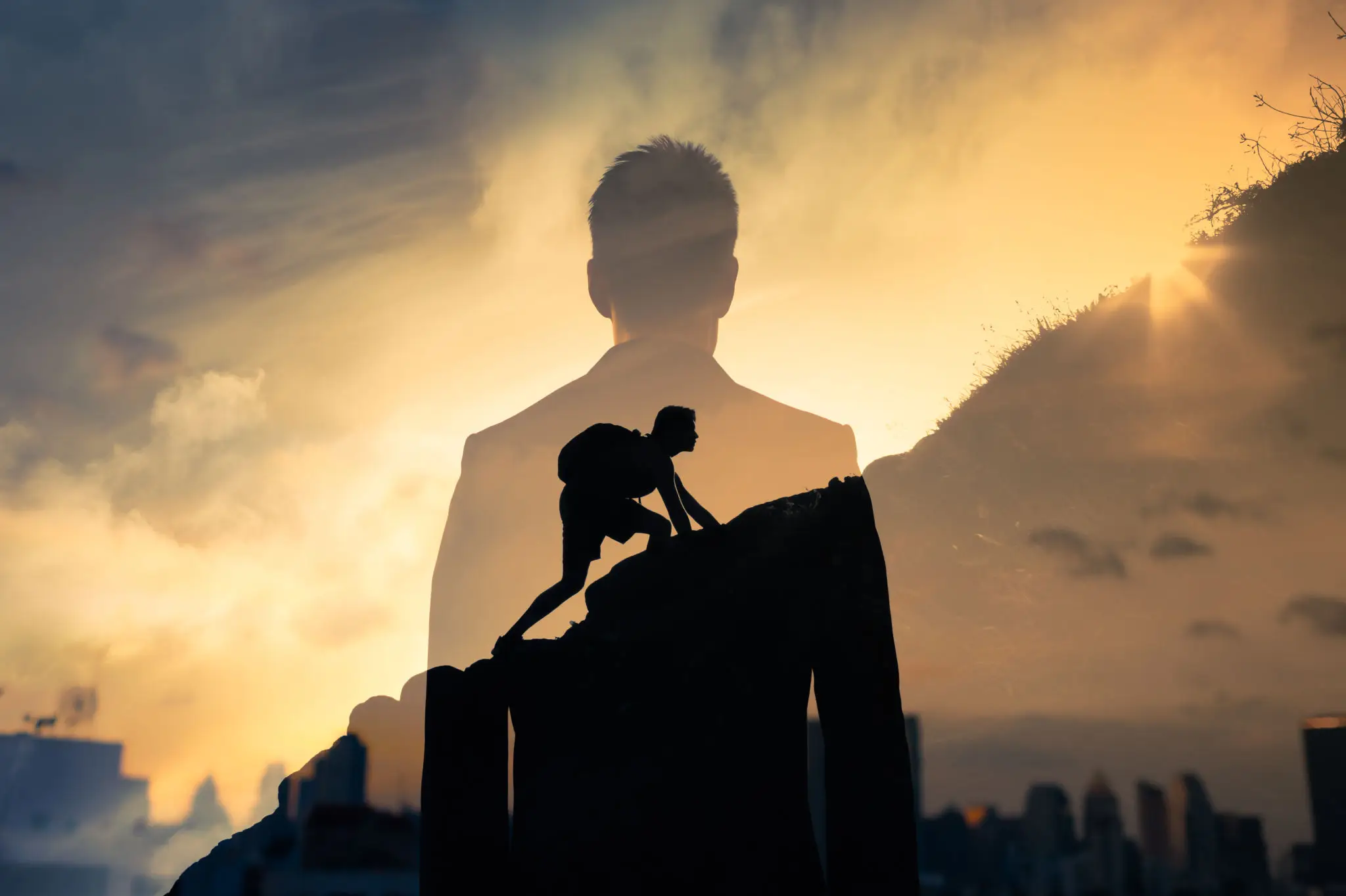 Silhouette of climber over urban skyline at sunset