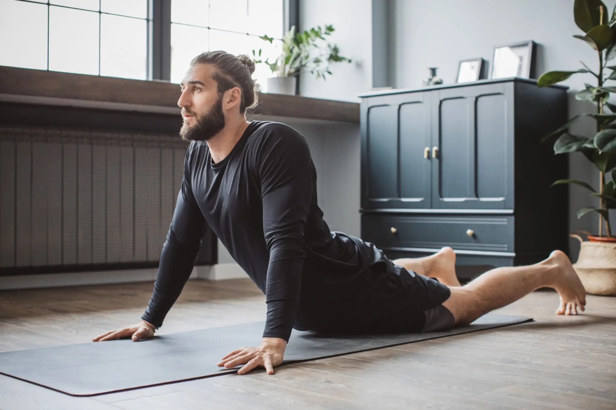 Man doing yoga cobra pose at home