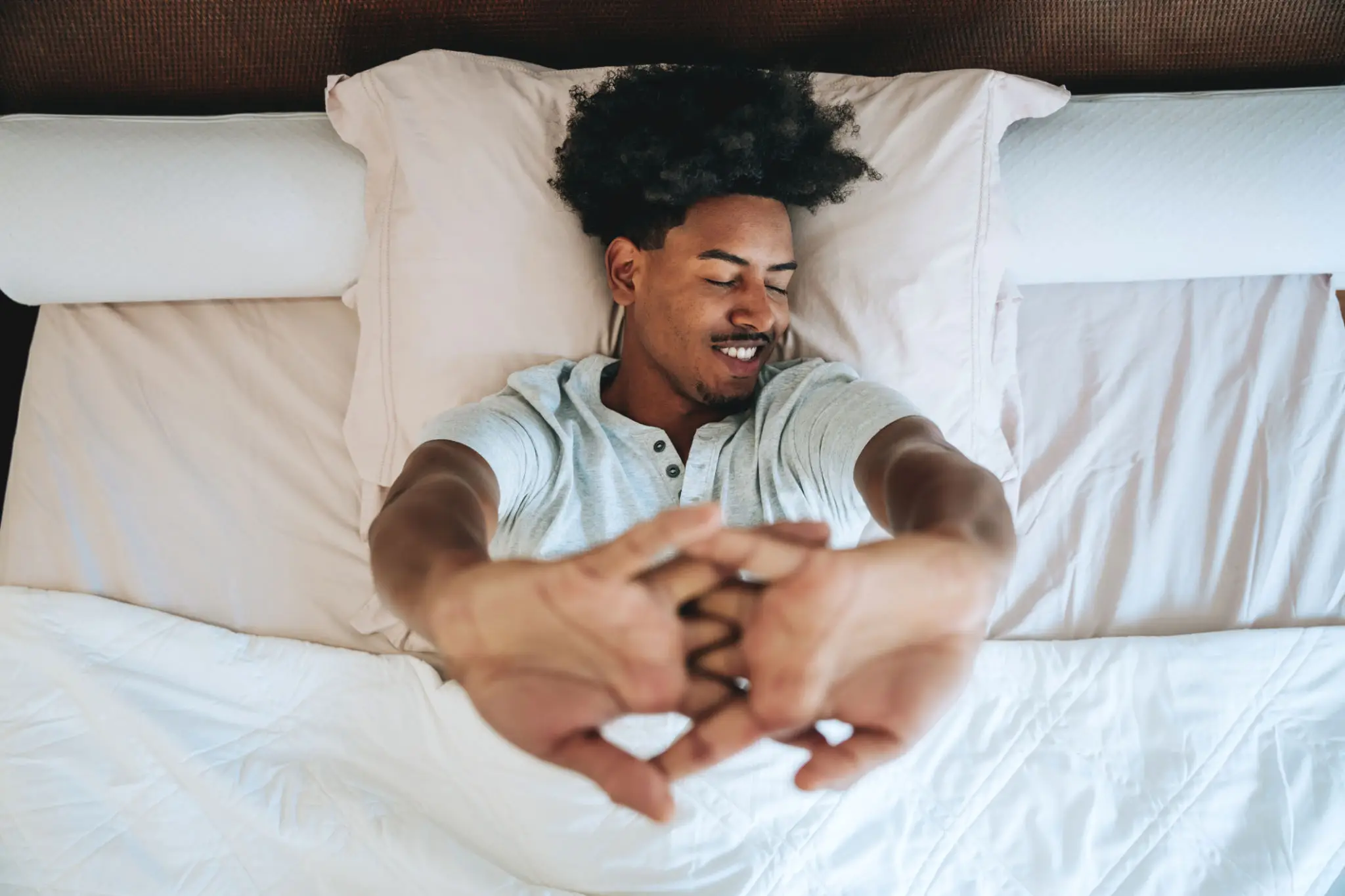 Smiling man stretching in bed