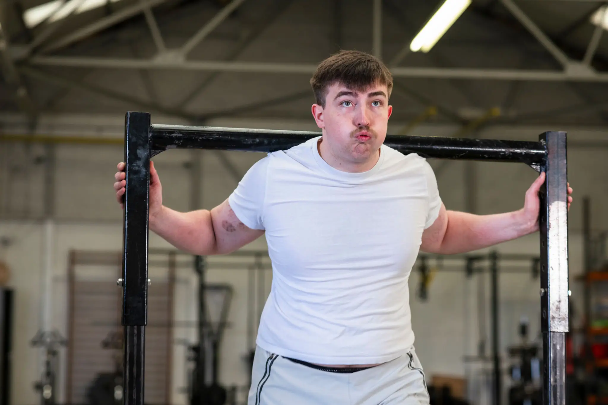 Young man squatting with barbell in gym