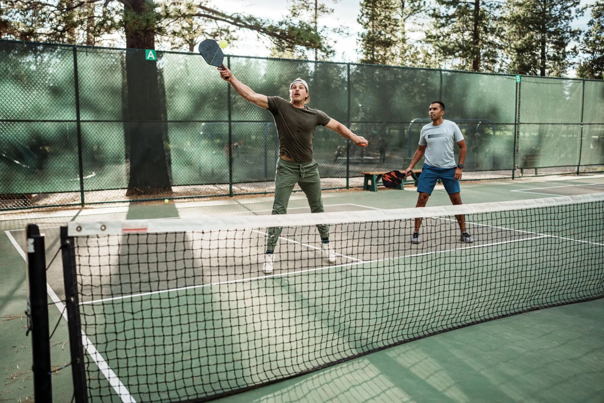 Two men playing pickleball on outdoor court