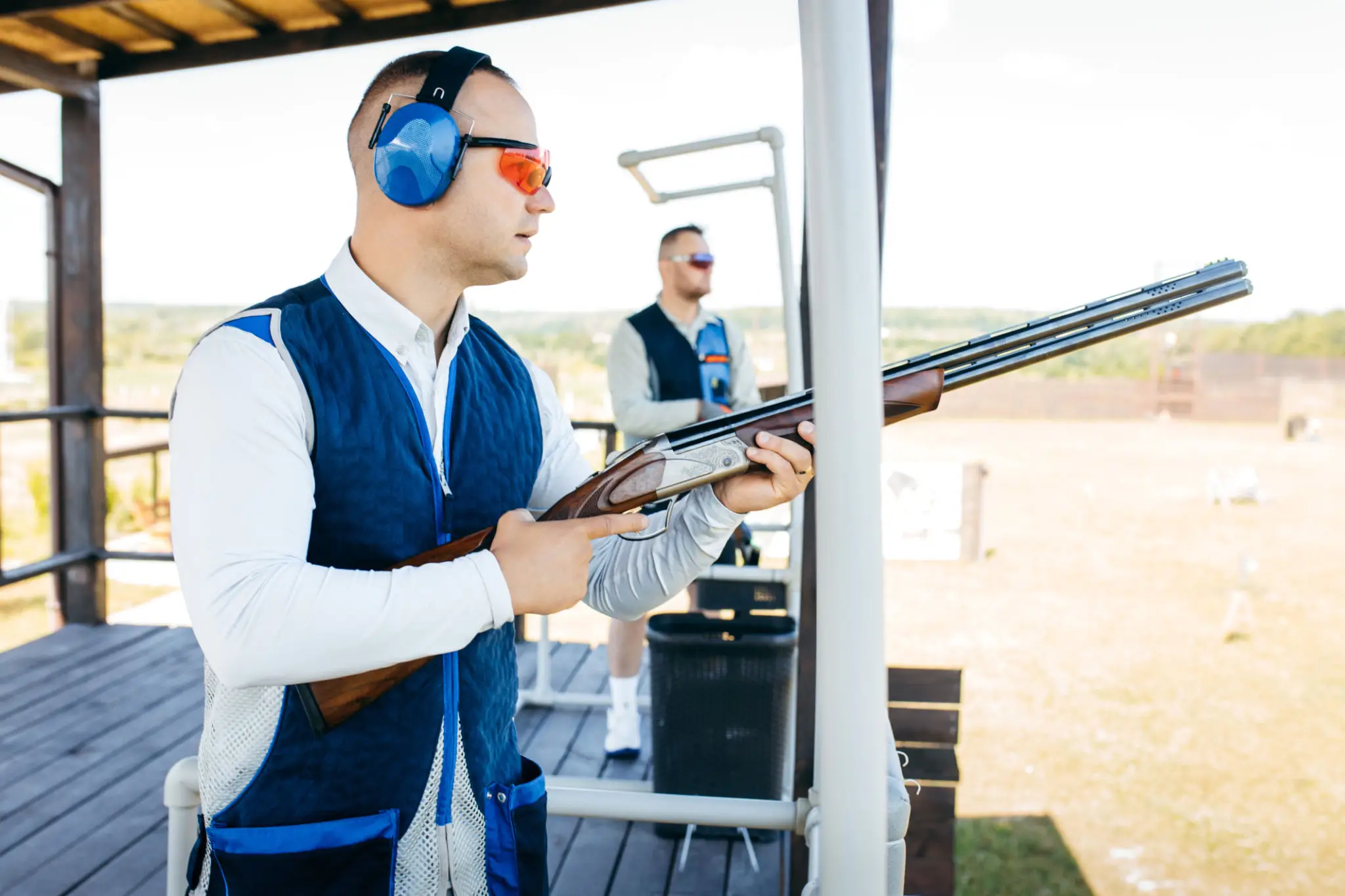 Man aiming shotgun at outdoor shooting range