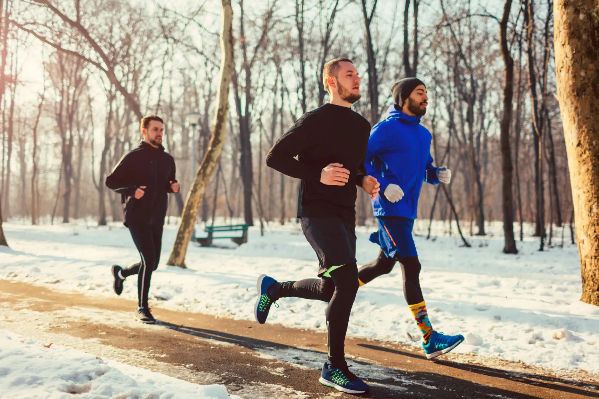 Three men running in snowy park