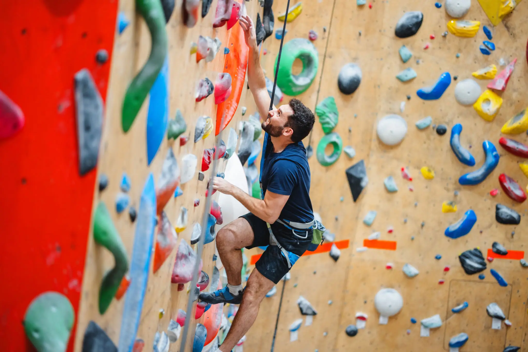 Man climbing indoor rock wall with colorful holds
