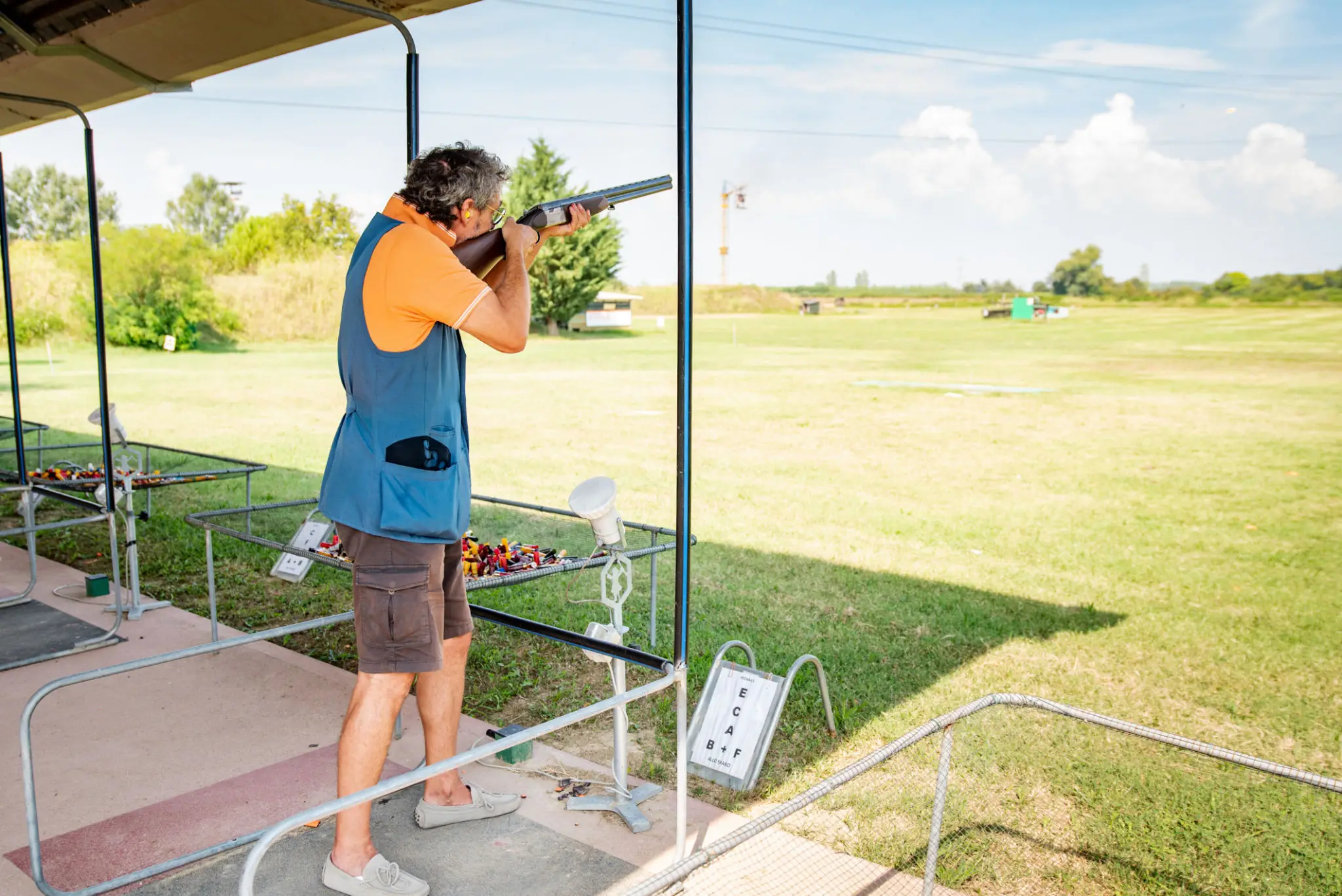 Man shooting shotgun at outdoor shooting range