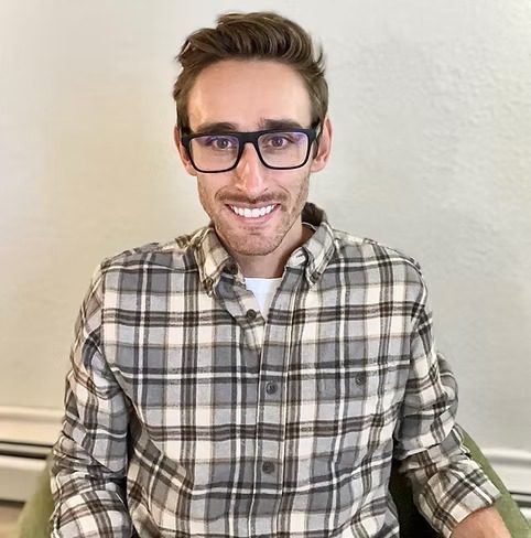 Smiling person wearing glasses and plaid shirt
