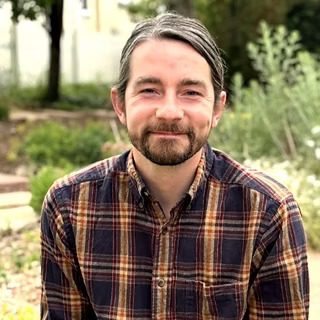 Smiling bearded man in plaid shirt outdoors