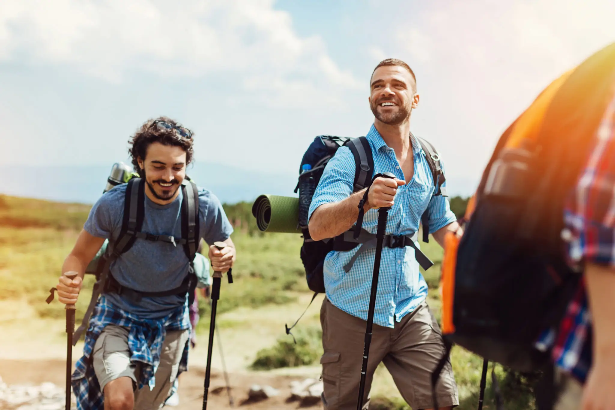 Two smiling men hiking with backpacks and poles
