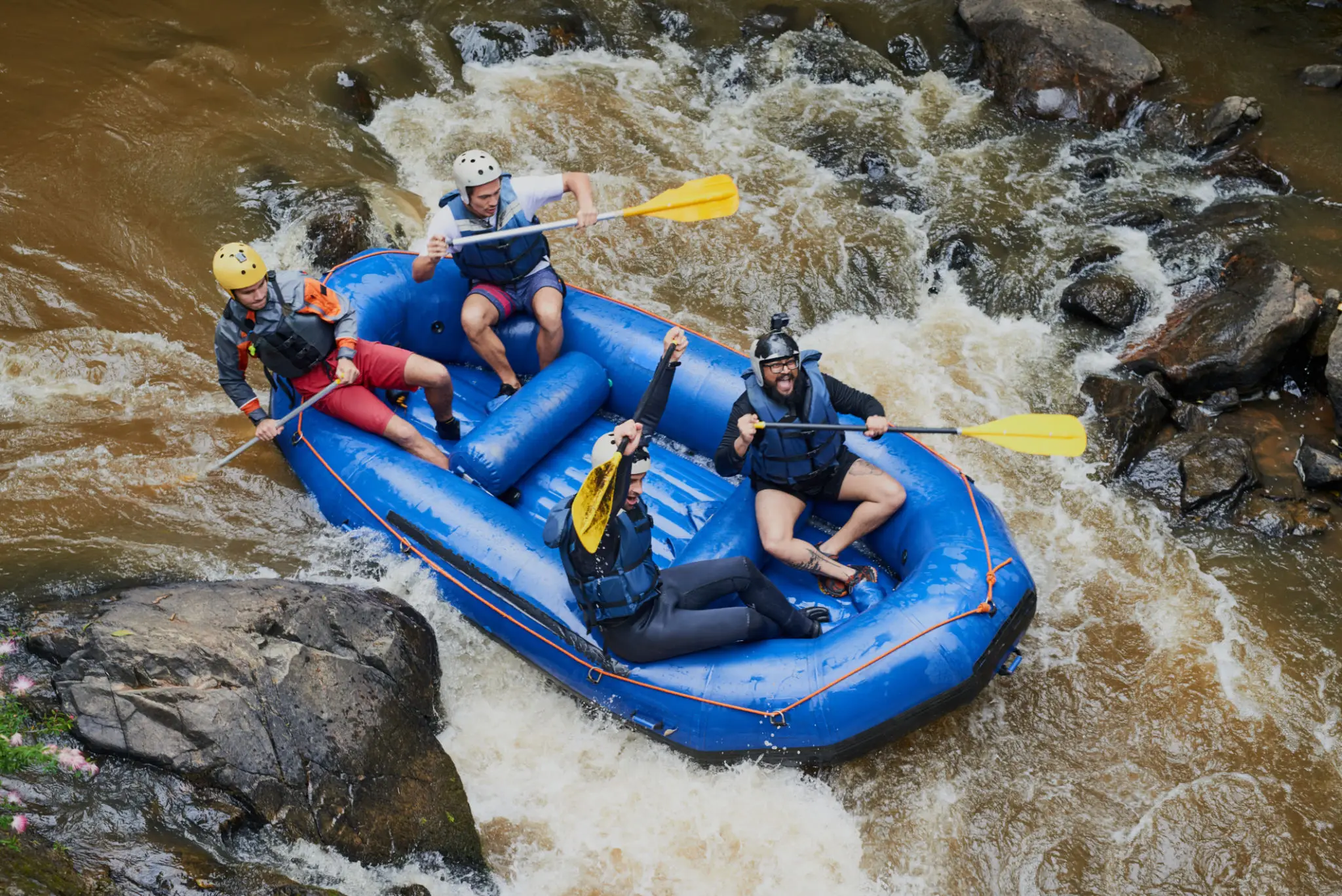 Four people whitewater rafting in blue raft