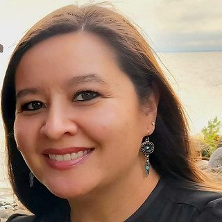 Smiling woman wearing dangling earrings by water