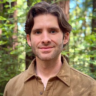 Smiling person with brown hair in forest