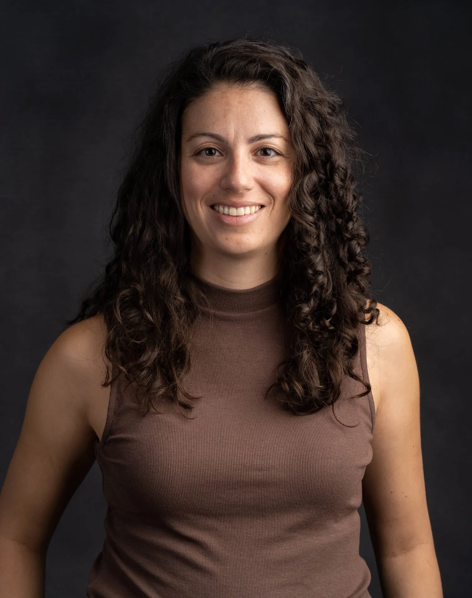 Smiling woman with curly hair wearing brown top