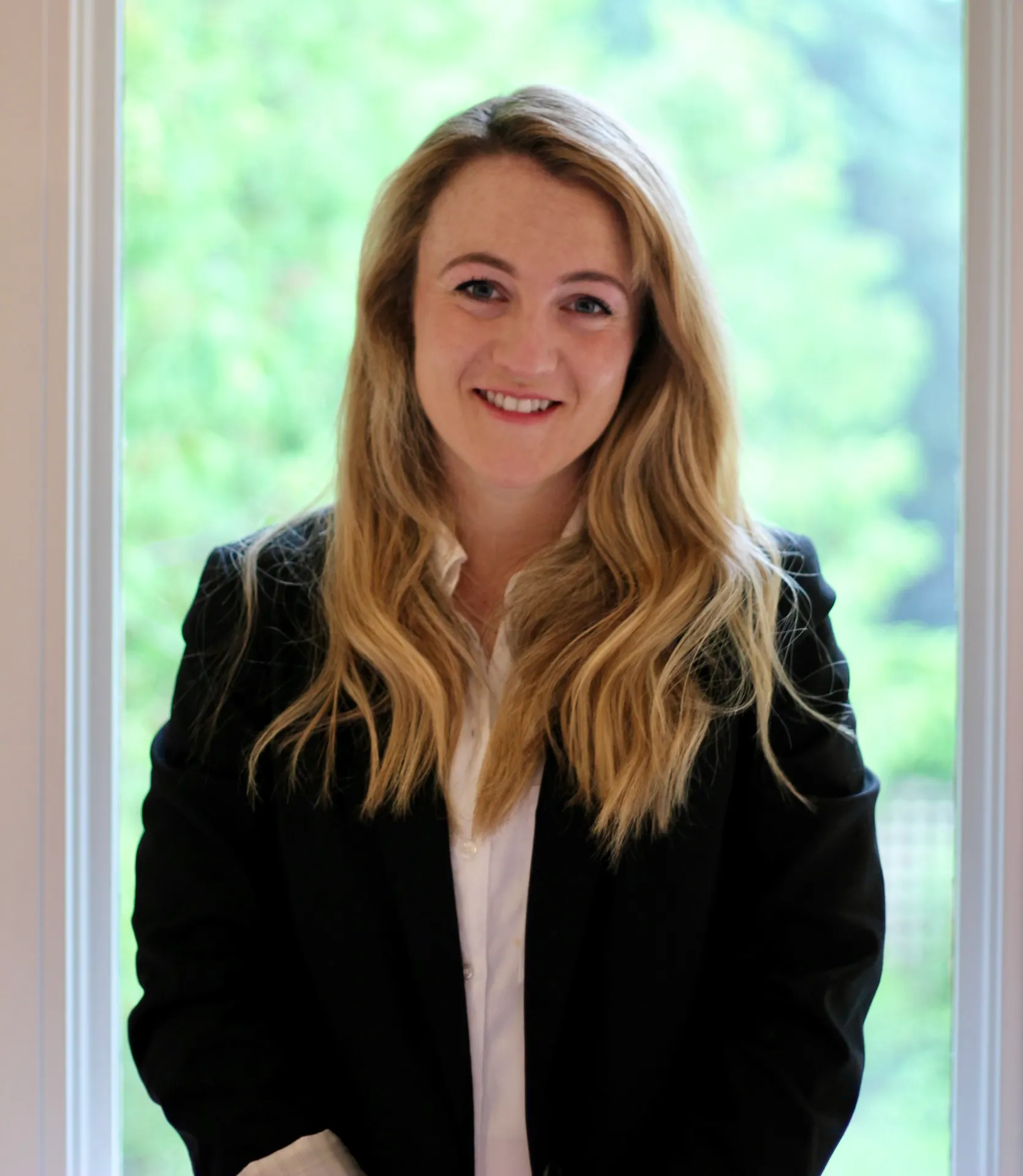 Smiling professional woman in blazer by window