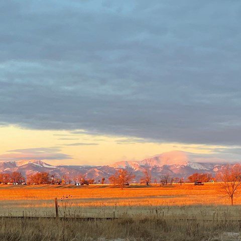 Golden sunset over snowy mountains and fields