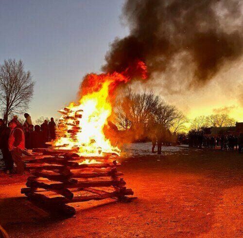 Large bonfire with crowd at dusk