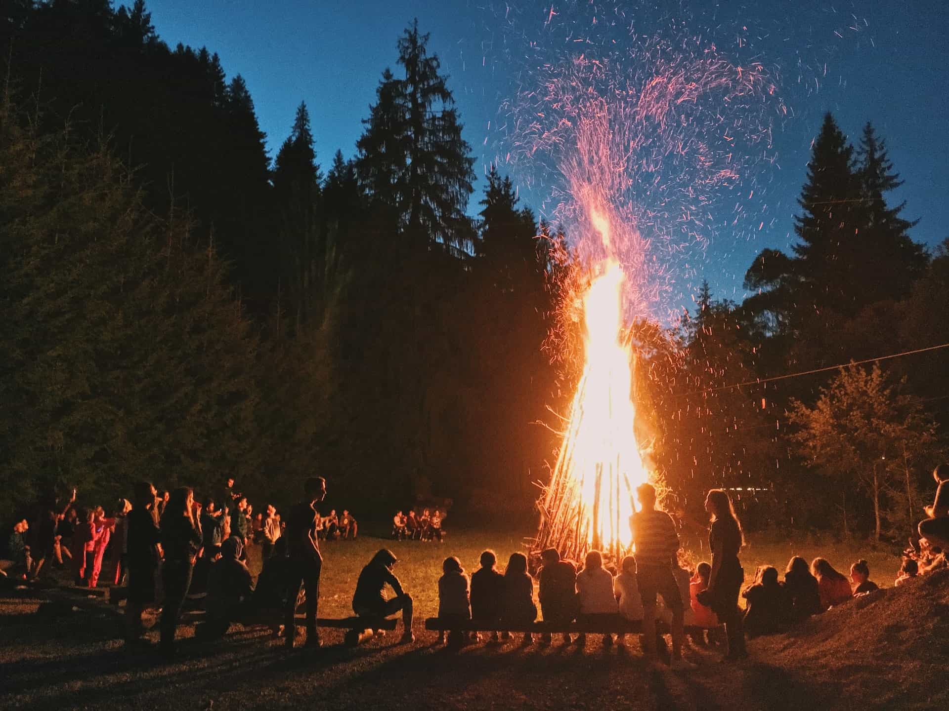 Night bonfire with people in forest clearing