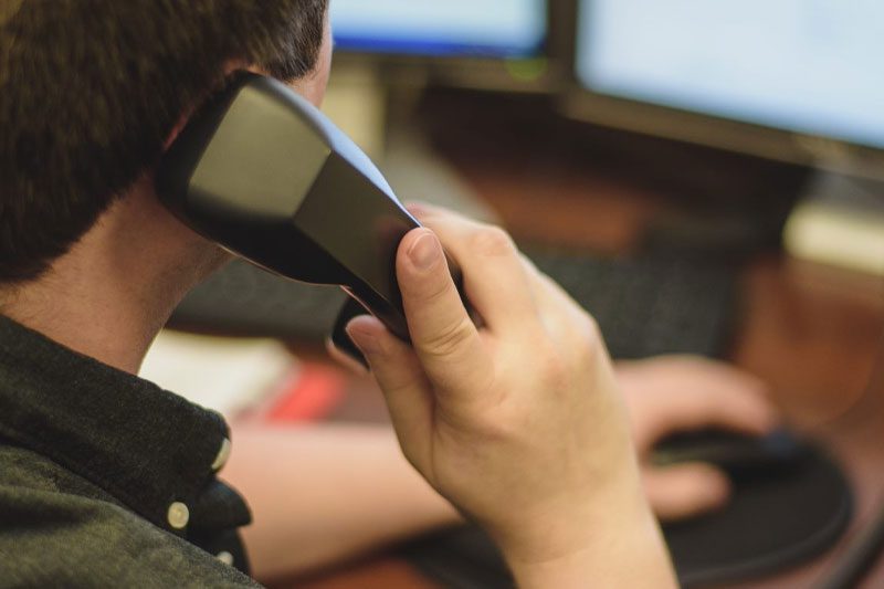 Person on phone at computer workstation