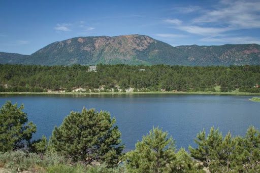 Mountain lake with pine trees and blue sky