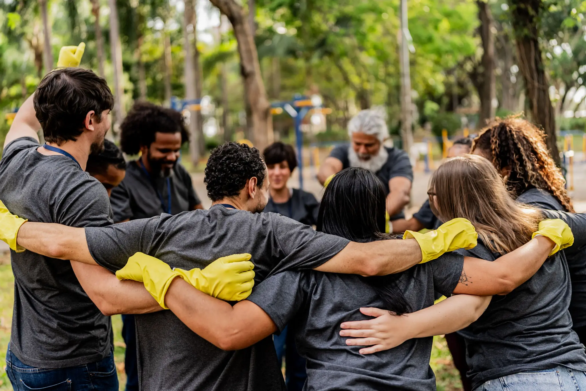 Volunteers huddling in park wearing yellow gloves