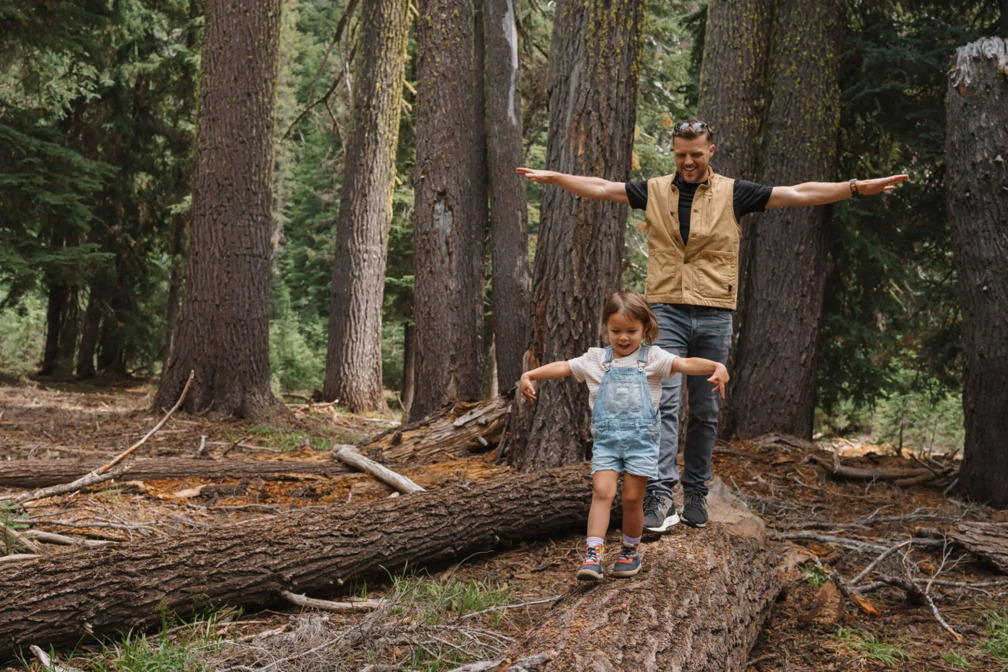 Man and child balancing on forest log
