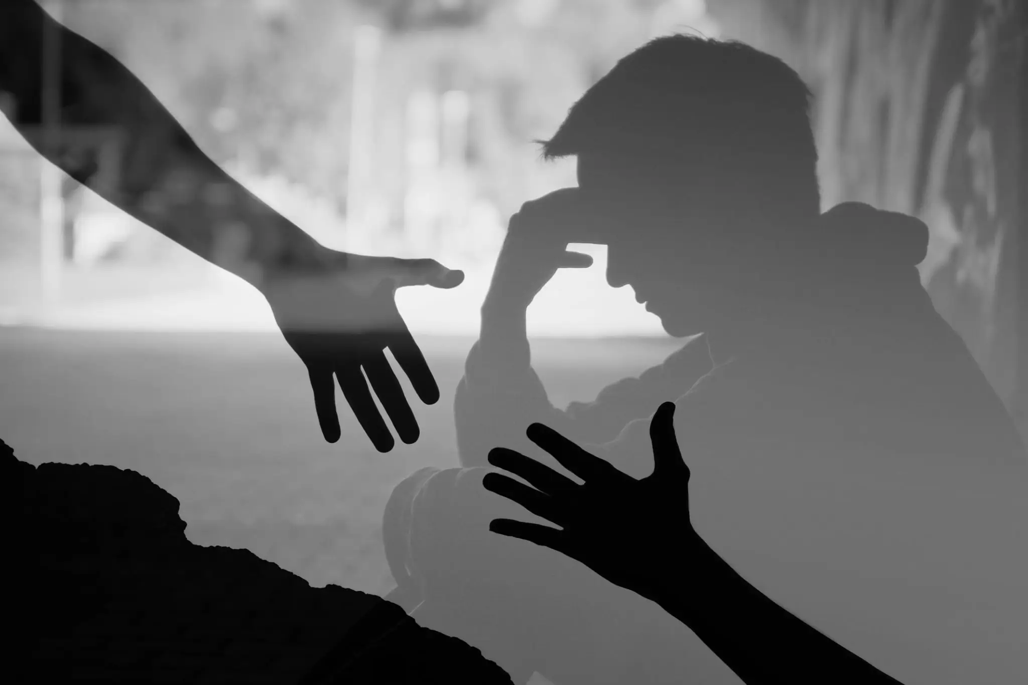 Silhouette of distressed person receiving helping hands