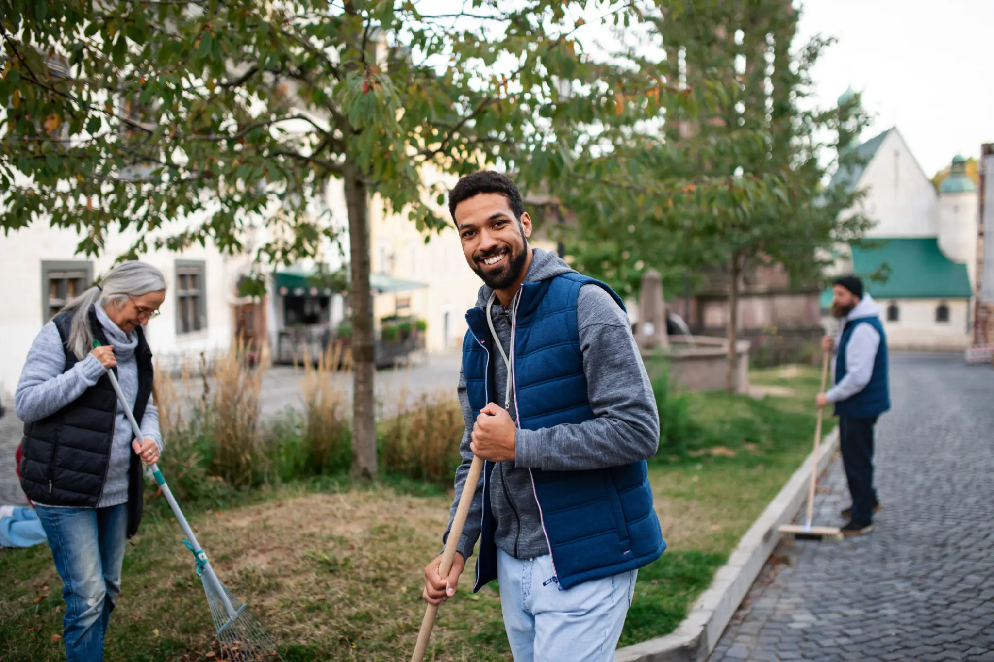 Smiling volunteer raking leaves in community cleanup