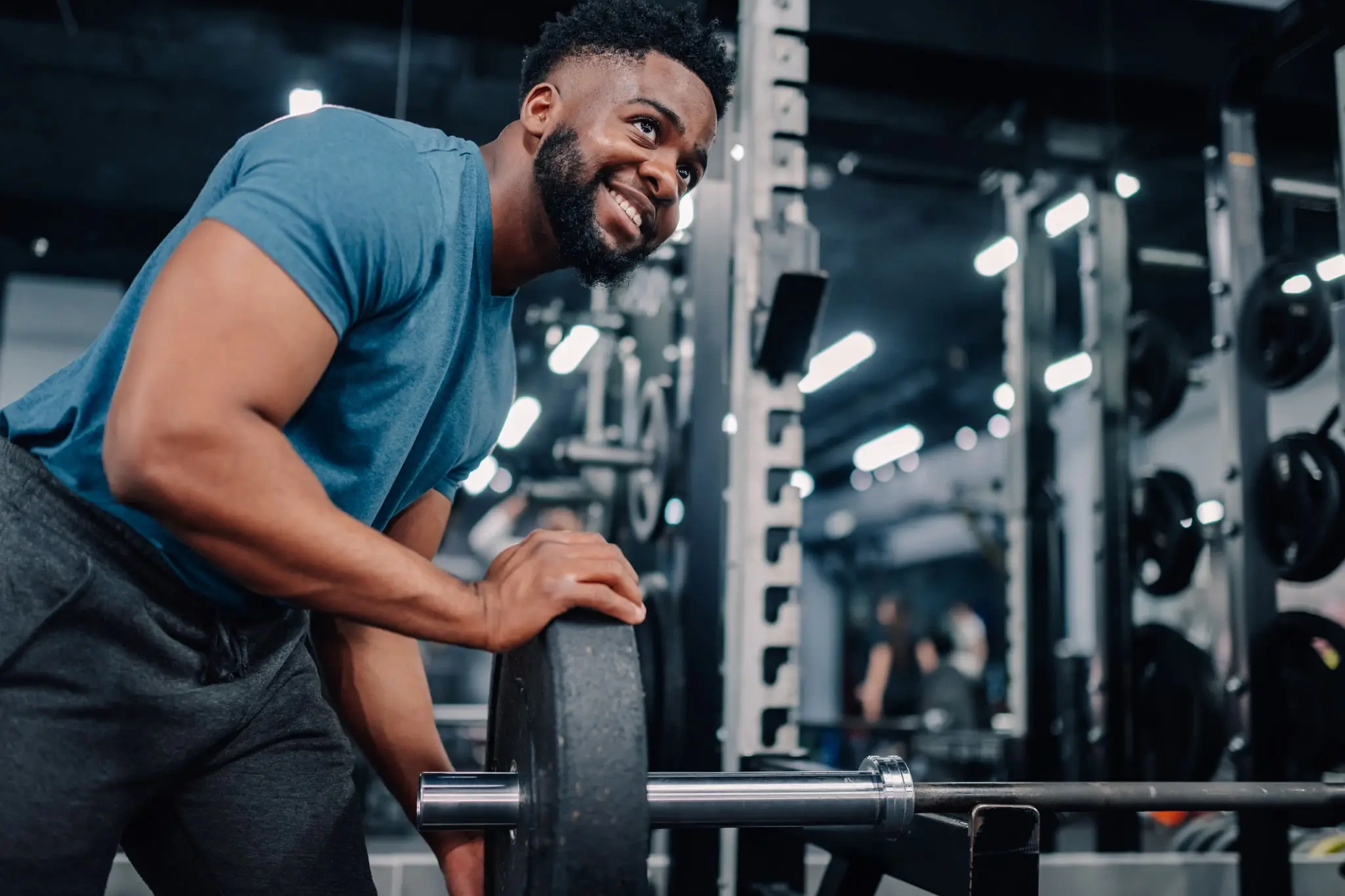 Smiling man loading barbell in gym