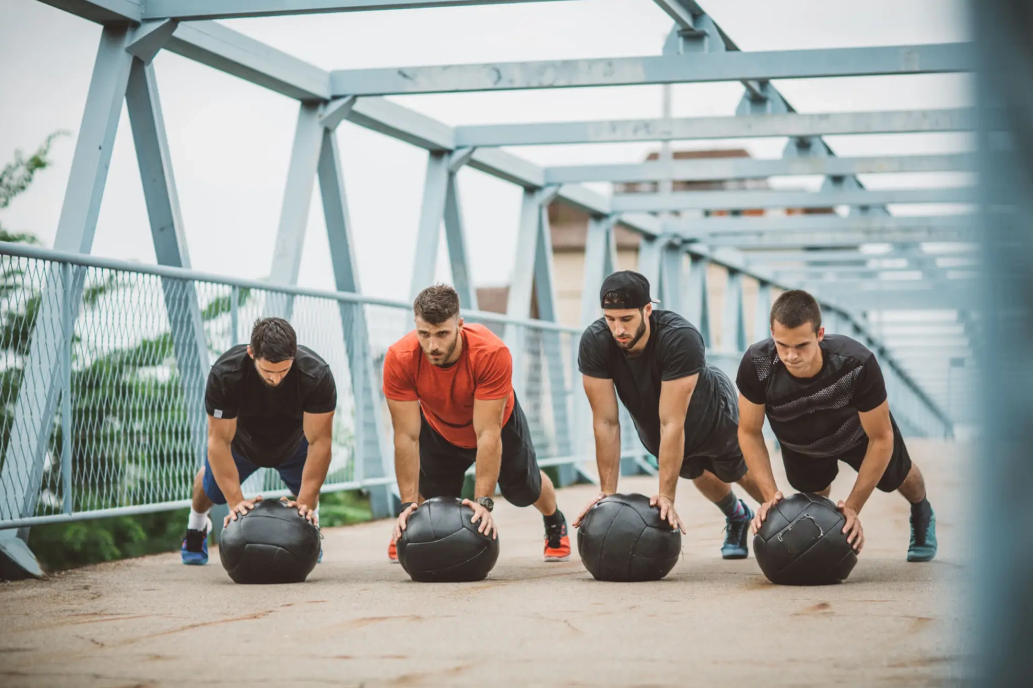 Four men doing medicine ball push-ups on bridge