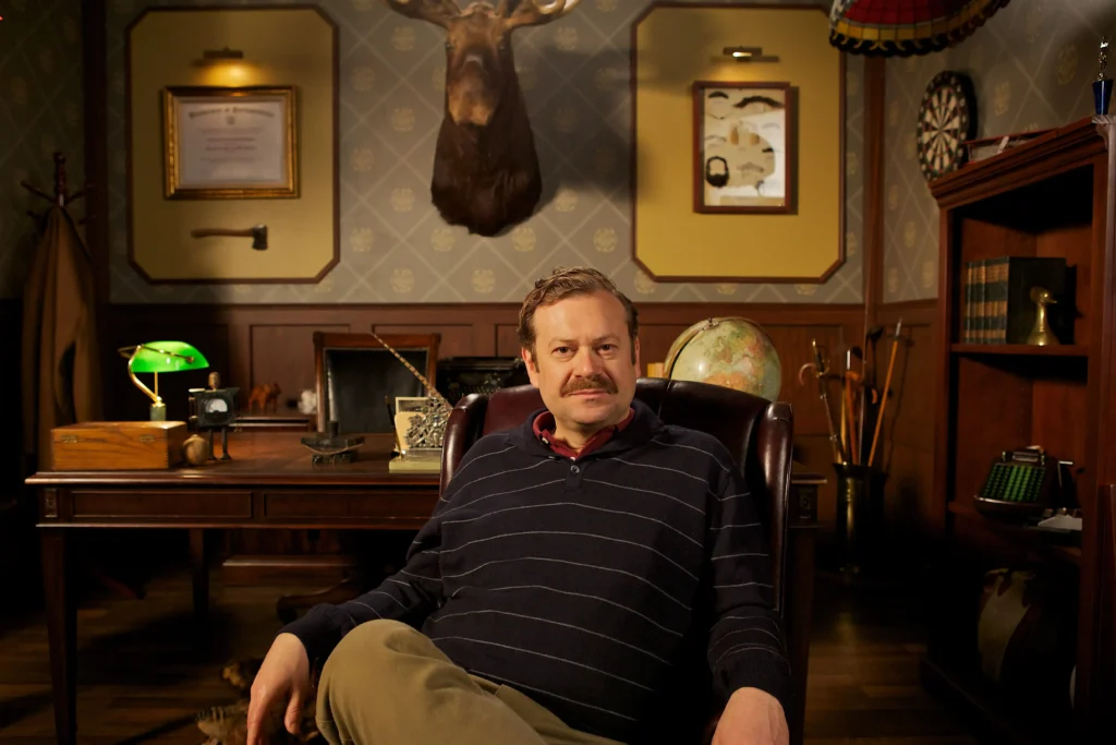Man seated in vintage wood-paneled study