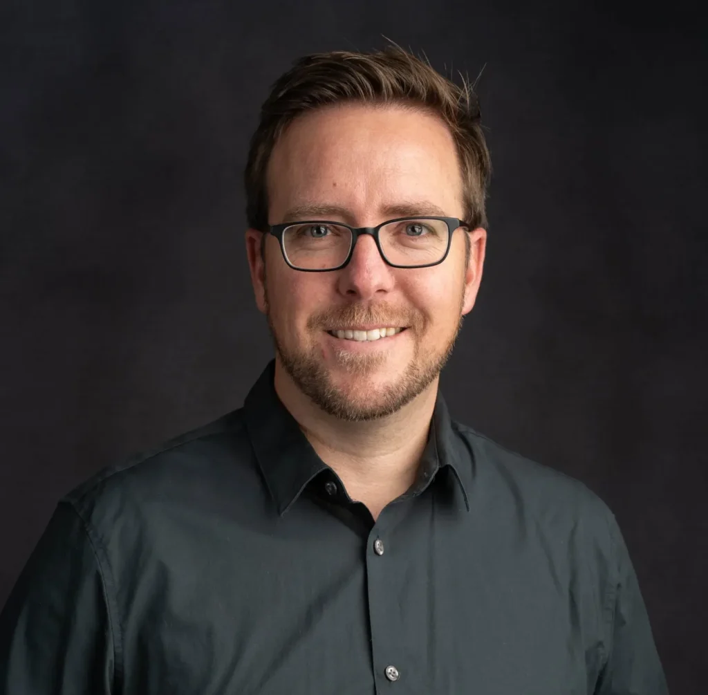Smiling man with glasses in dark shirt