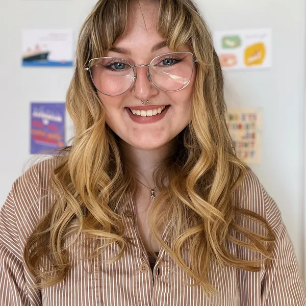 Smiling person with glasses, curly hair, striped shirt