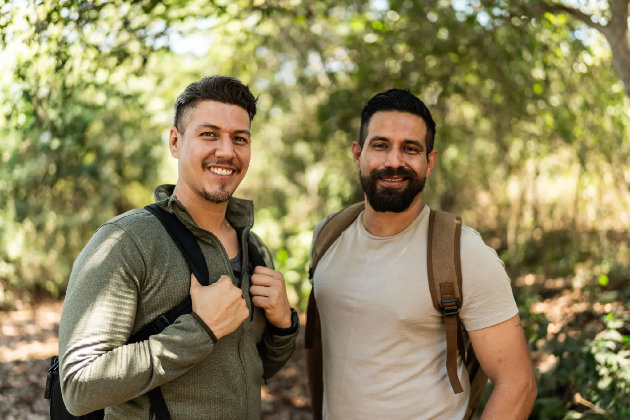 Two smiling men with backpacks in forest