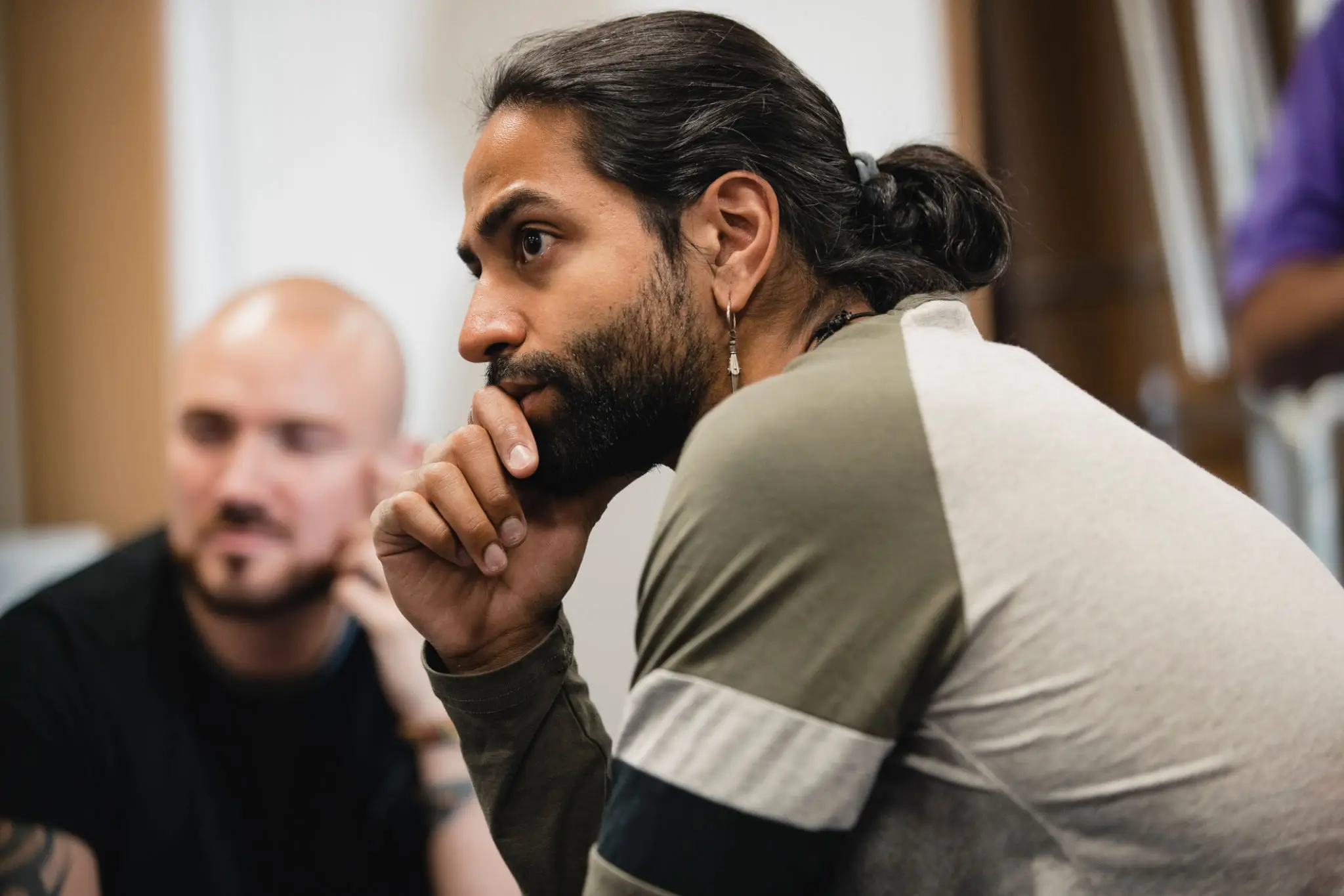 Thoughtful man with bun and earring in meeting